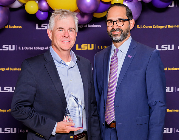 Jonathan "Mike" Morgan holds his award next to former LSU Ourso Dean Jared Llorens