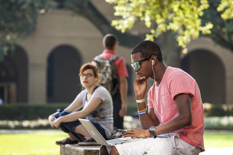 student sitting on a bench in the quad