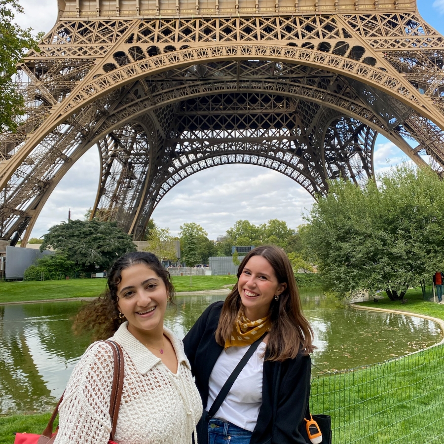 two students stand in front of the Eiffel Tower
