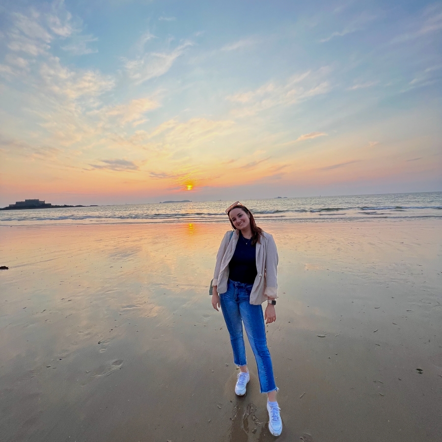 student smiles on beach at sunset