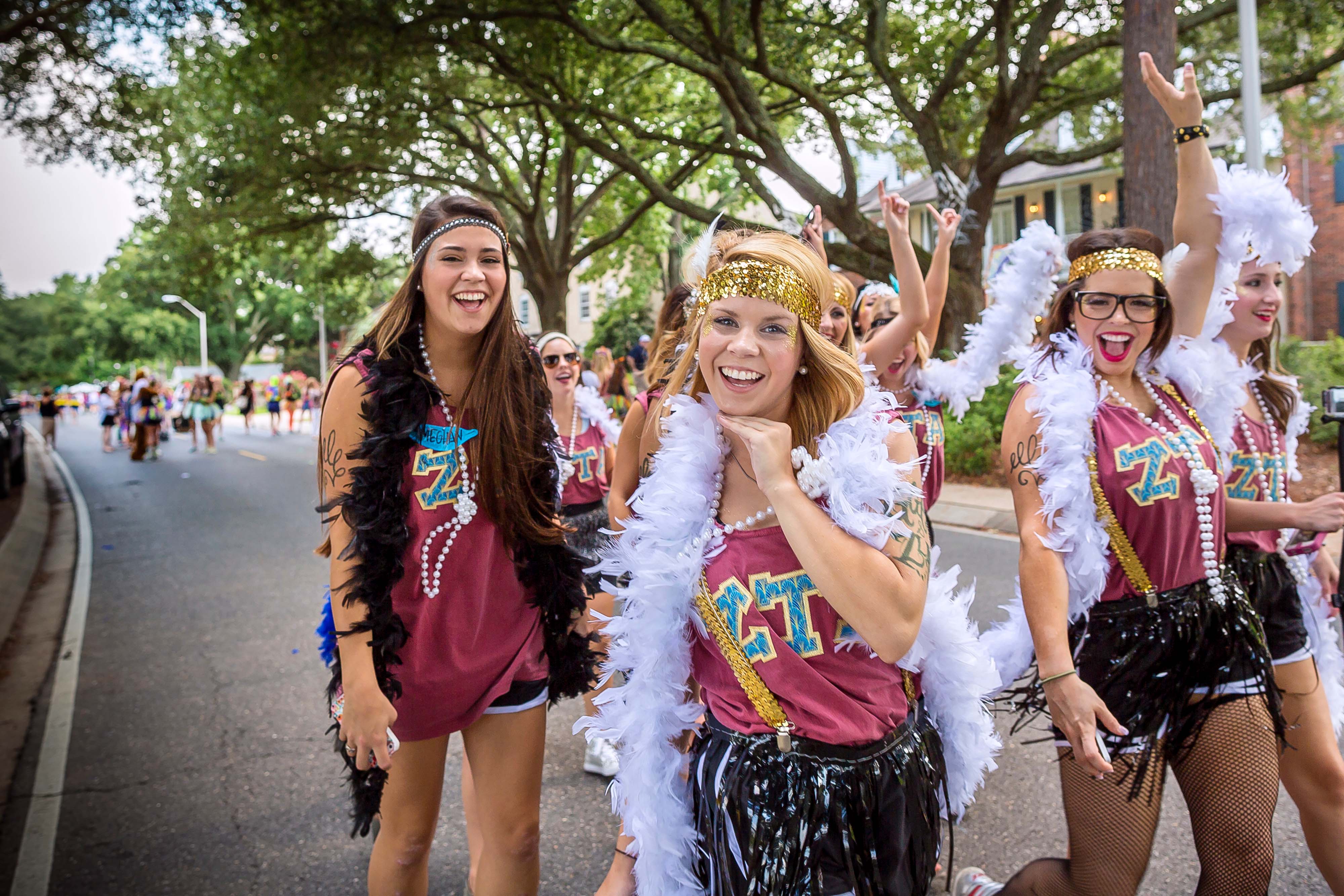 zeta members walk in front of Greek houses